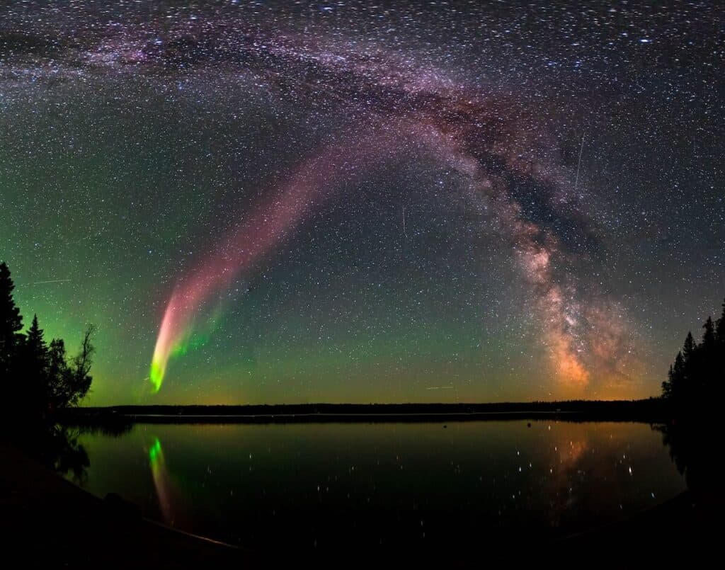 Northern lights and milky way galaxy visible at night above a lake in Voyageurs National Park