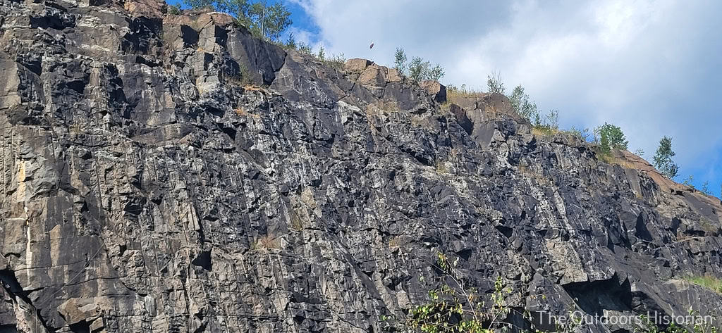 A close-up of the face of Silver Creek Cliff, where vertical lines show where workers drilled holes to drop pieces of dynamite and blast the cliff face. This is an interesting example of how some marks in the rock reflect recent human activity.